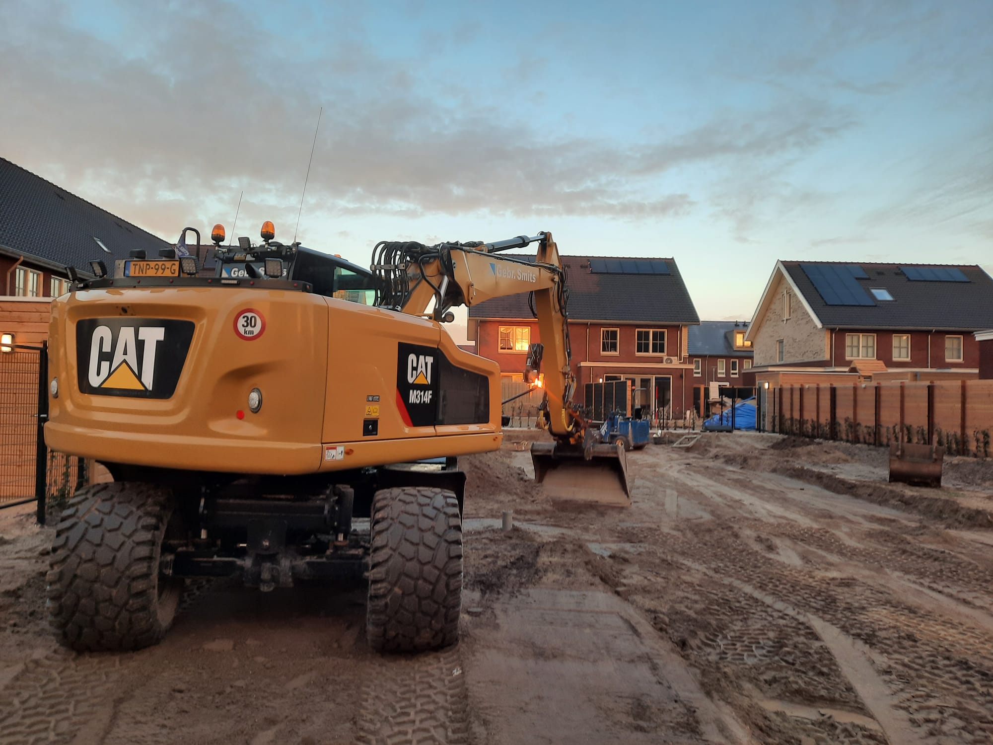 Mobiele kraan van Gebr. Smits bij schemer in een nieuwbouwstraat