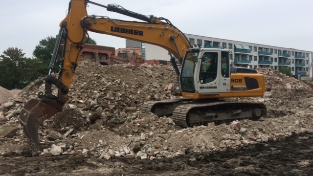 Rupskraan op een berg puin voor een appartementengebouw